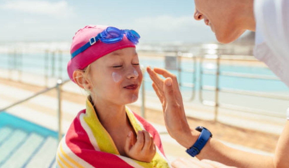 A parent gently applying moisturizer to a child’s arm after swimming.